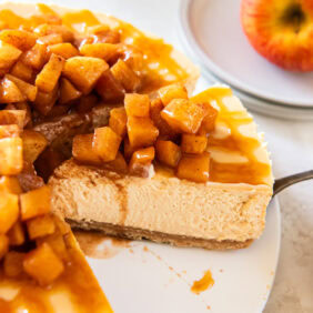 Caramel apple cheesecake being served from a white cake plate.