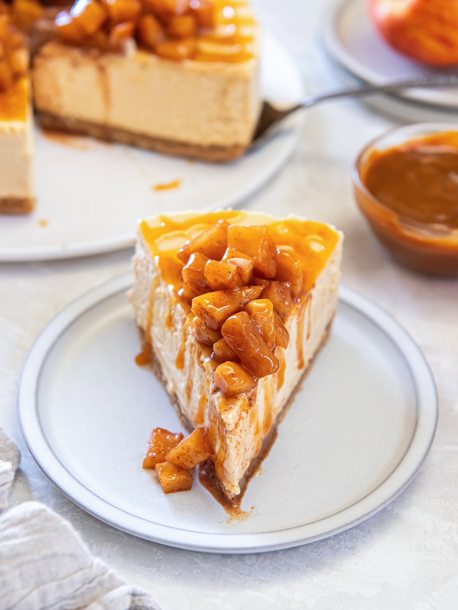Slice of caramel apple cheesecake on a white plate.