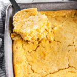 Serving cornbread pudding out of a casserole dish.