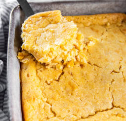 Serving cornbread pudding out of a casserole dish.