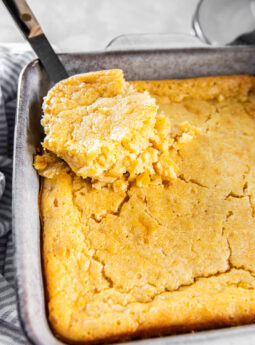 Serving cornbread pudding out of a casserole dish.