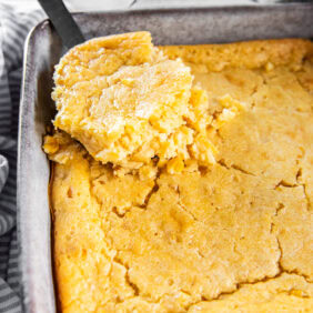 Serving cornbread pudding out of a casserole dish.