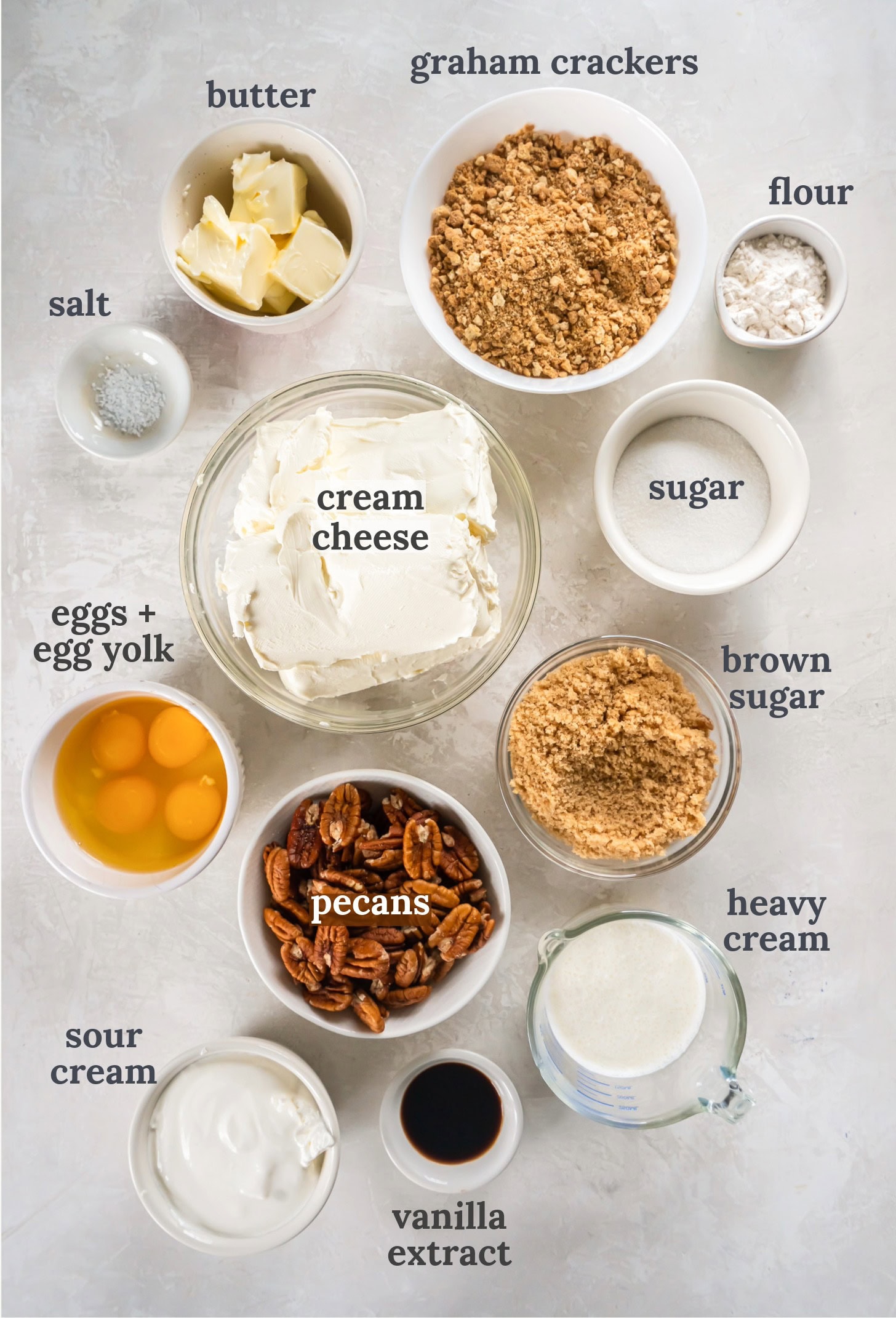 Small bowls with sugar, cream cheese, eggs, butter, sour cream and pecans.