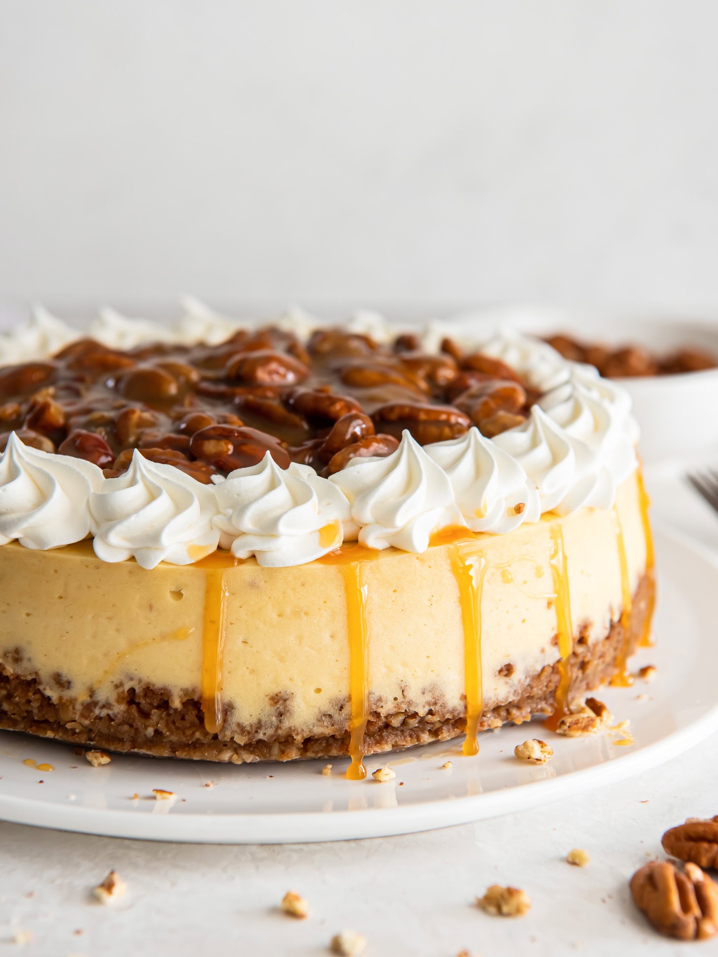 Pecan praline cheesecake topped with a pecan sauce and whipped cream.
