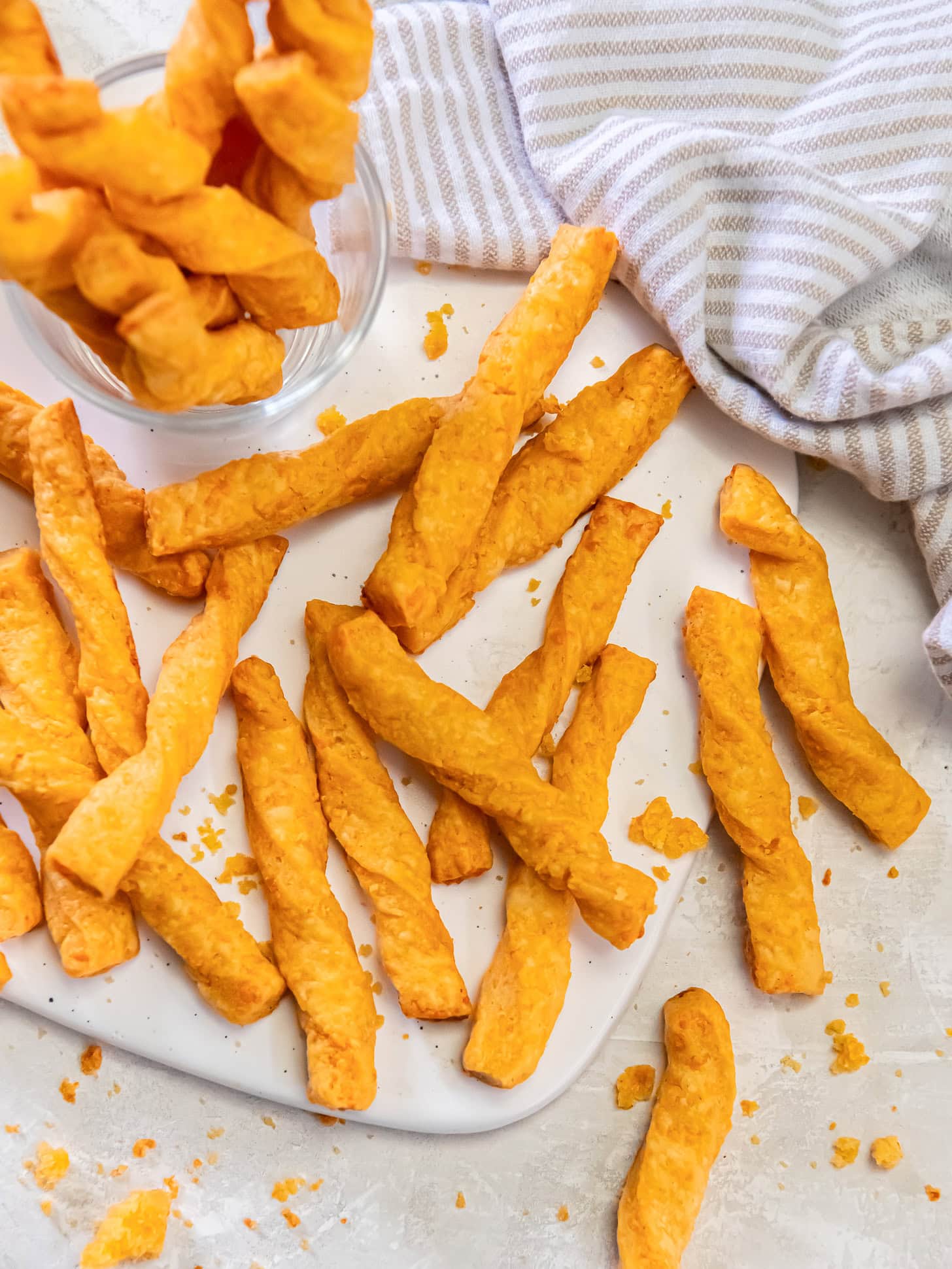Twisted cheese straws scattered on a white serving plate.