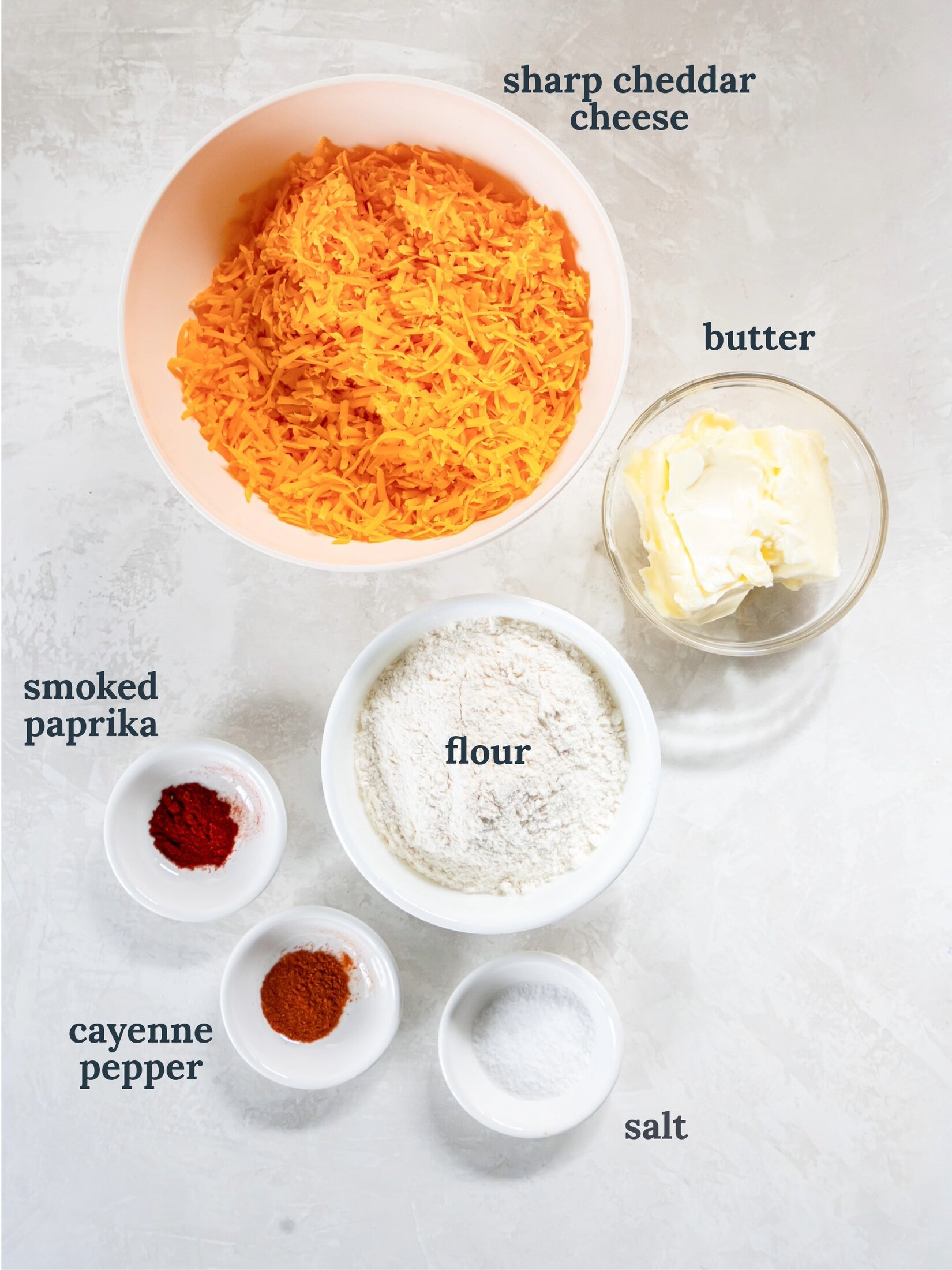 Bowls with shredded cheese, butter, flour and spices.