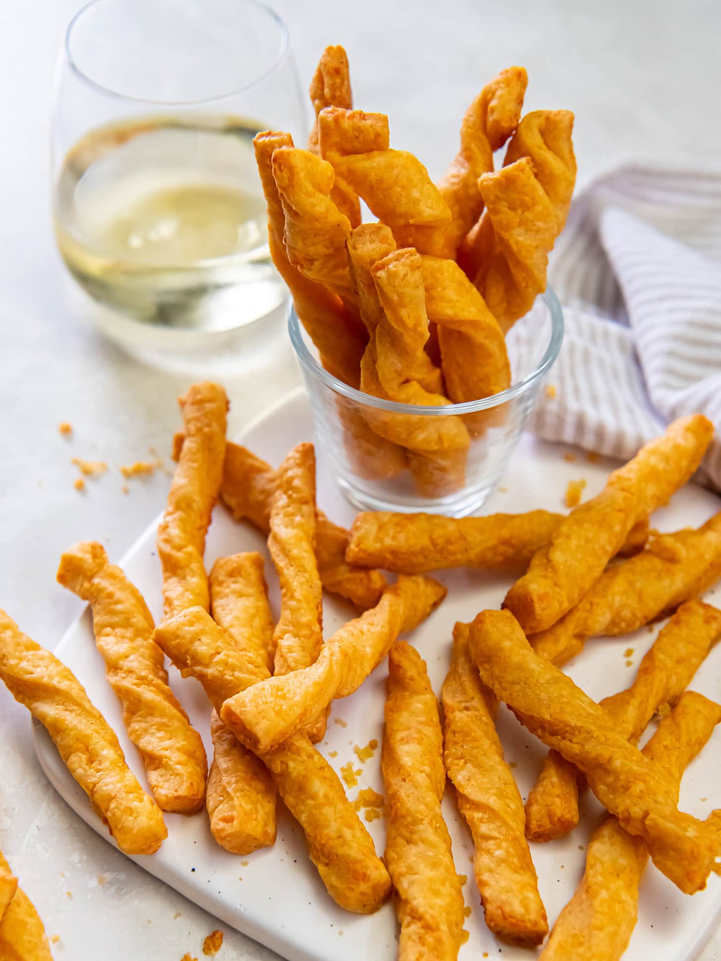 Twisted cheese straws served with a glass of white wine.