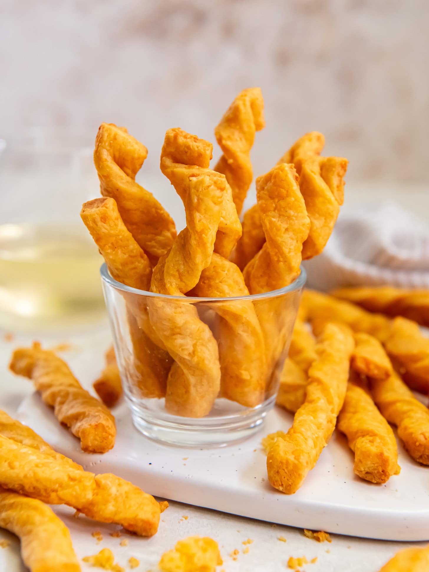 Cheddar cheese straws sticking up out of a small glass.