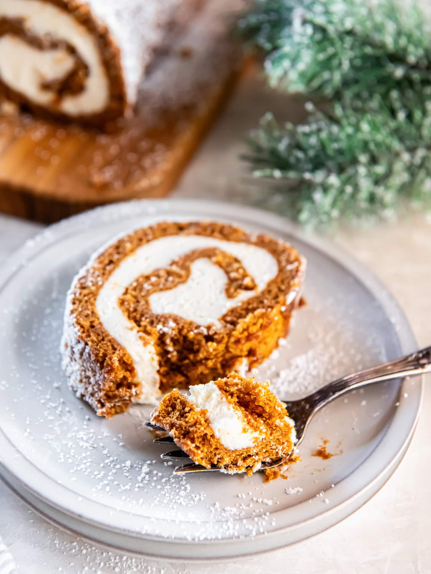 Slice of gingerbread cake roll on a plate with a fork.