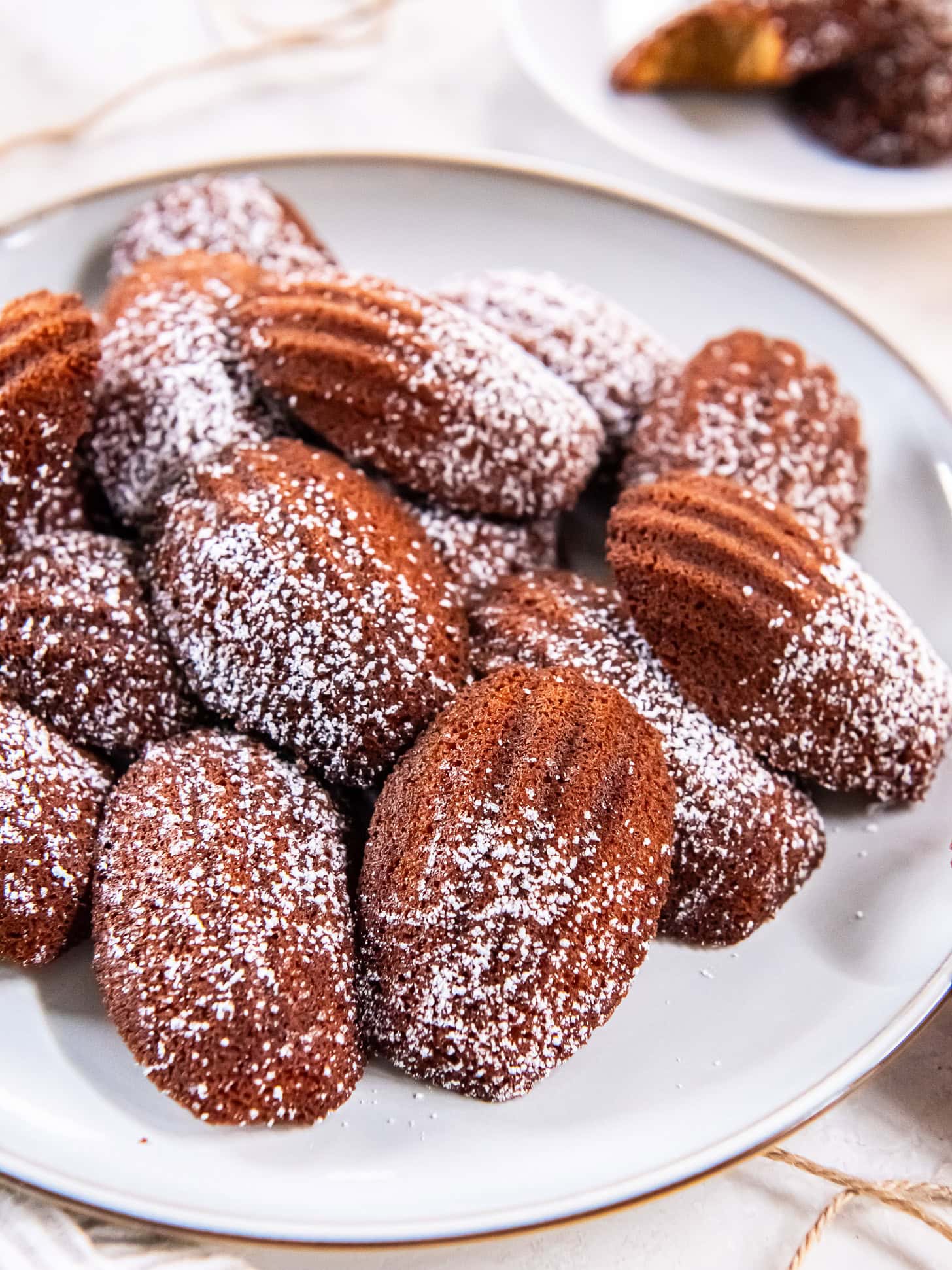 Gingerbread Madeleines dusted with powdered sugar on a white plate.