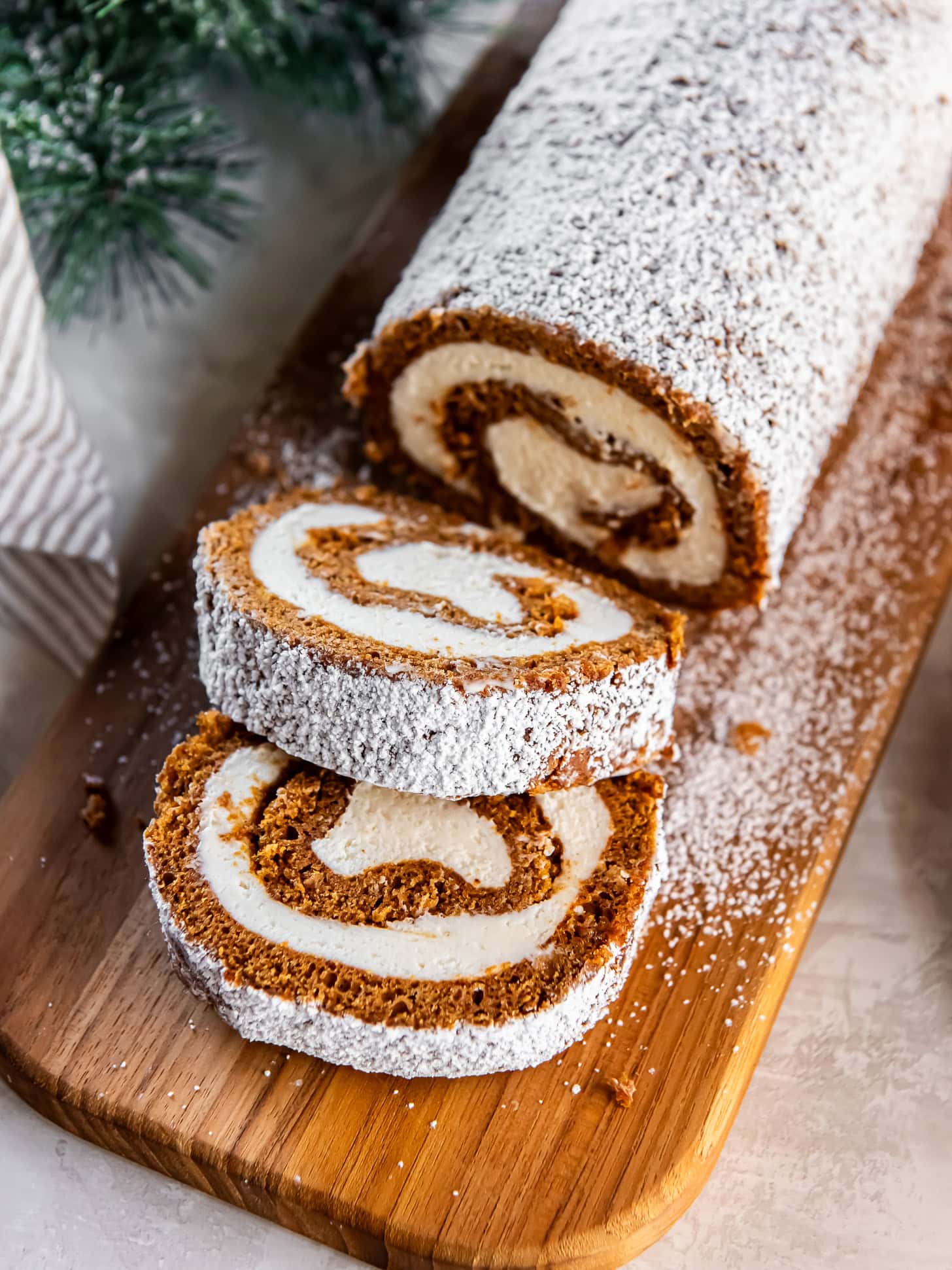 Sliced gingerbread Swiss roll cake on a wooden cutting board.