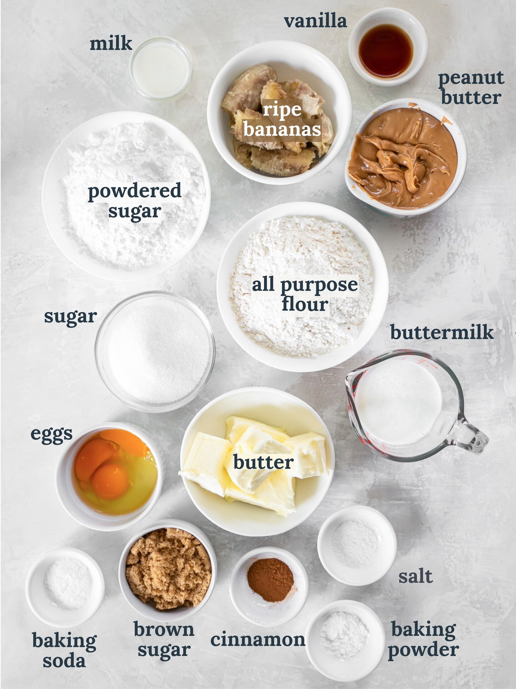 Small bowls with butter, flour, powdered sugar, eggs, peanut butter and ripe banana slices.