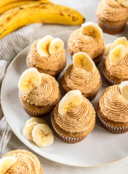 Banana cupcakes topped with peanut butter frosting and a banana slice for garnish.