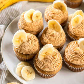 Banana cupcakes topped with peanut butter frosting and a banana slice for garnish.