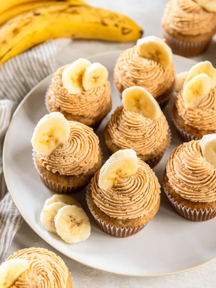 Banana cupcakes topped with peanut butter frosting and a banana slice for garnish. 