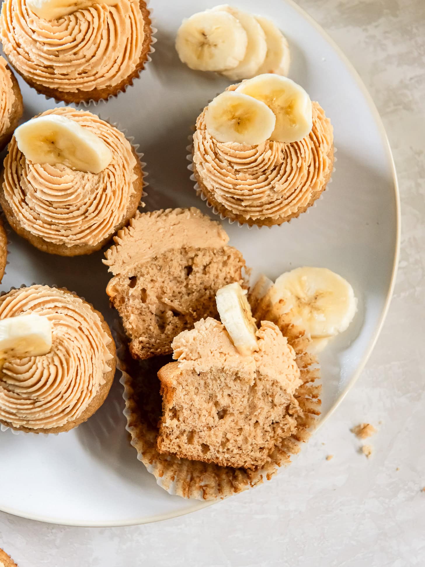 Banana cupcakes on a white plate with one cut in half.