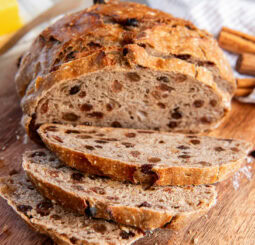 No knead cinnamon raisin bread sliced on a cutting board.