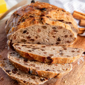 No knead cinnamon raisin bread sliced on a cutting board.