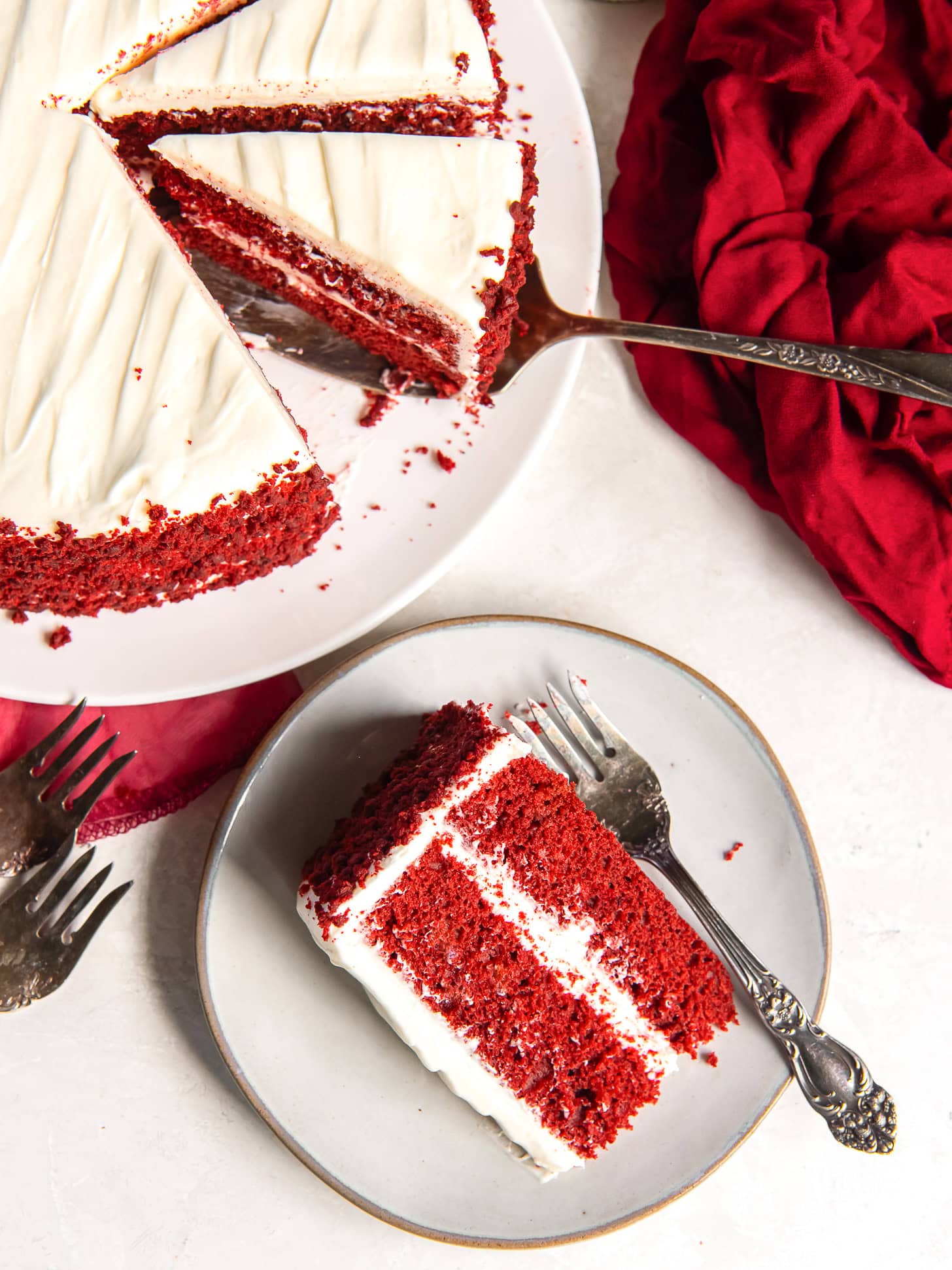 Slice of red velvet cake served on a white plate with a fork.