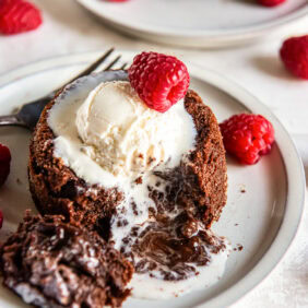 Chocolate lava cake cut into with a gooey molten center flowing onto the plate.