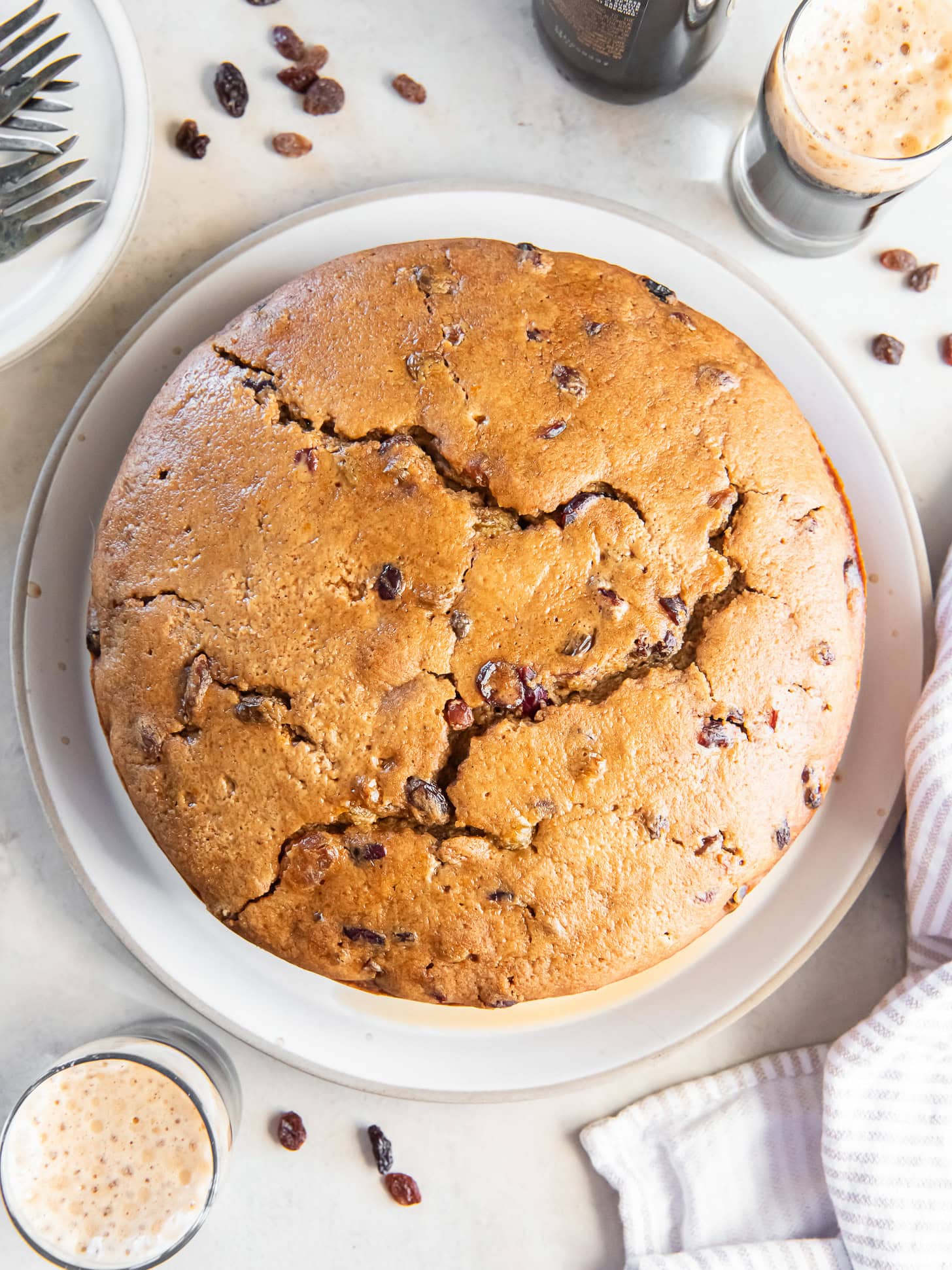 An Irish porter cake on a white serving plate near a glass of porter beer.