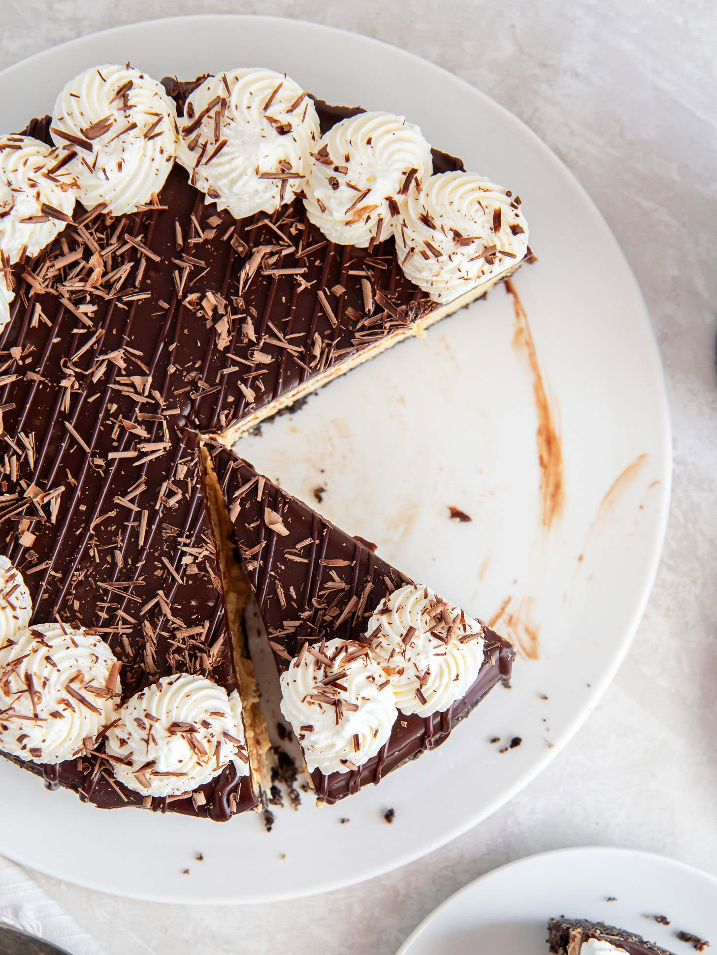 Slice taken out of a Bailey's cheesecake with chocolate ganache on top.