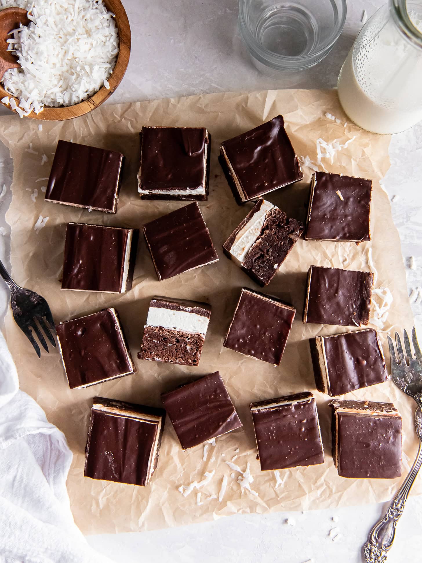 Layered coconut brownies on parchment paper.