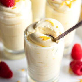 Glass with lemon mousse with a spoon inside.