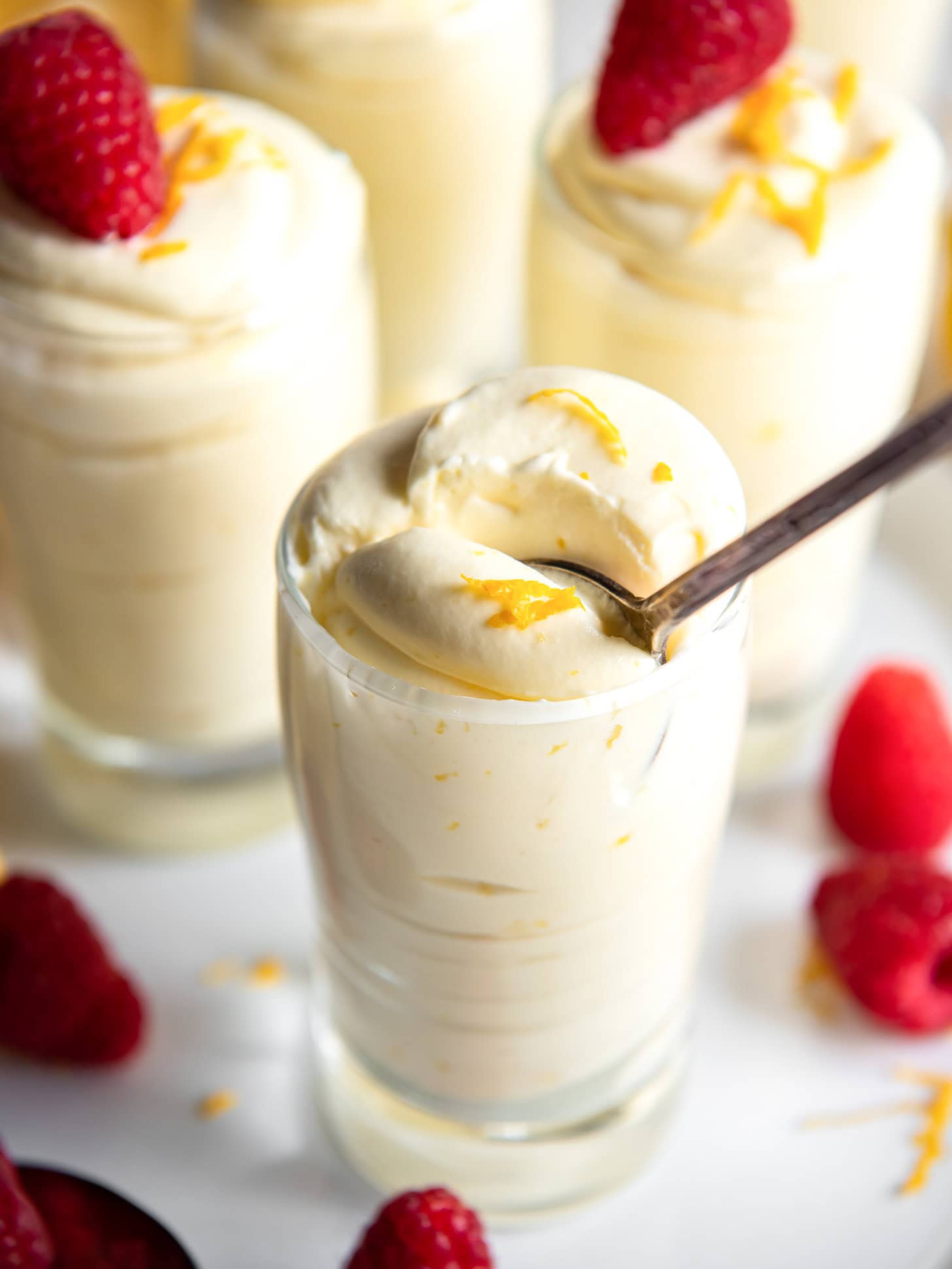 Glass with lemon mousse with a spoon inside.