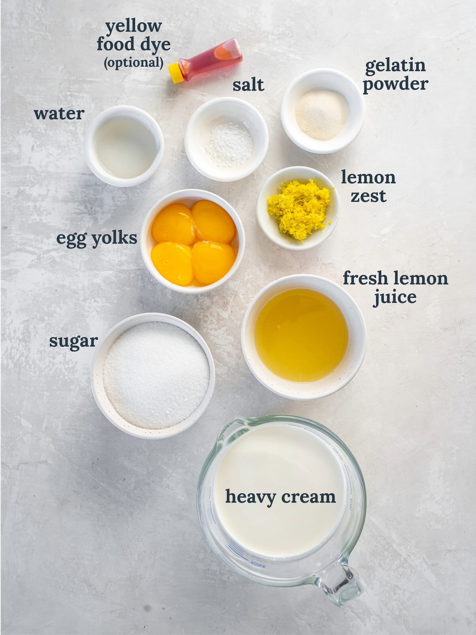 Small bowls with cream, egg yolks, sugar, lemon juice and zest.