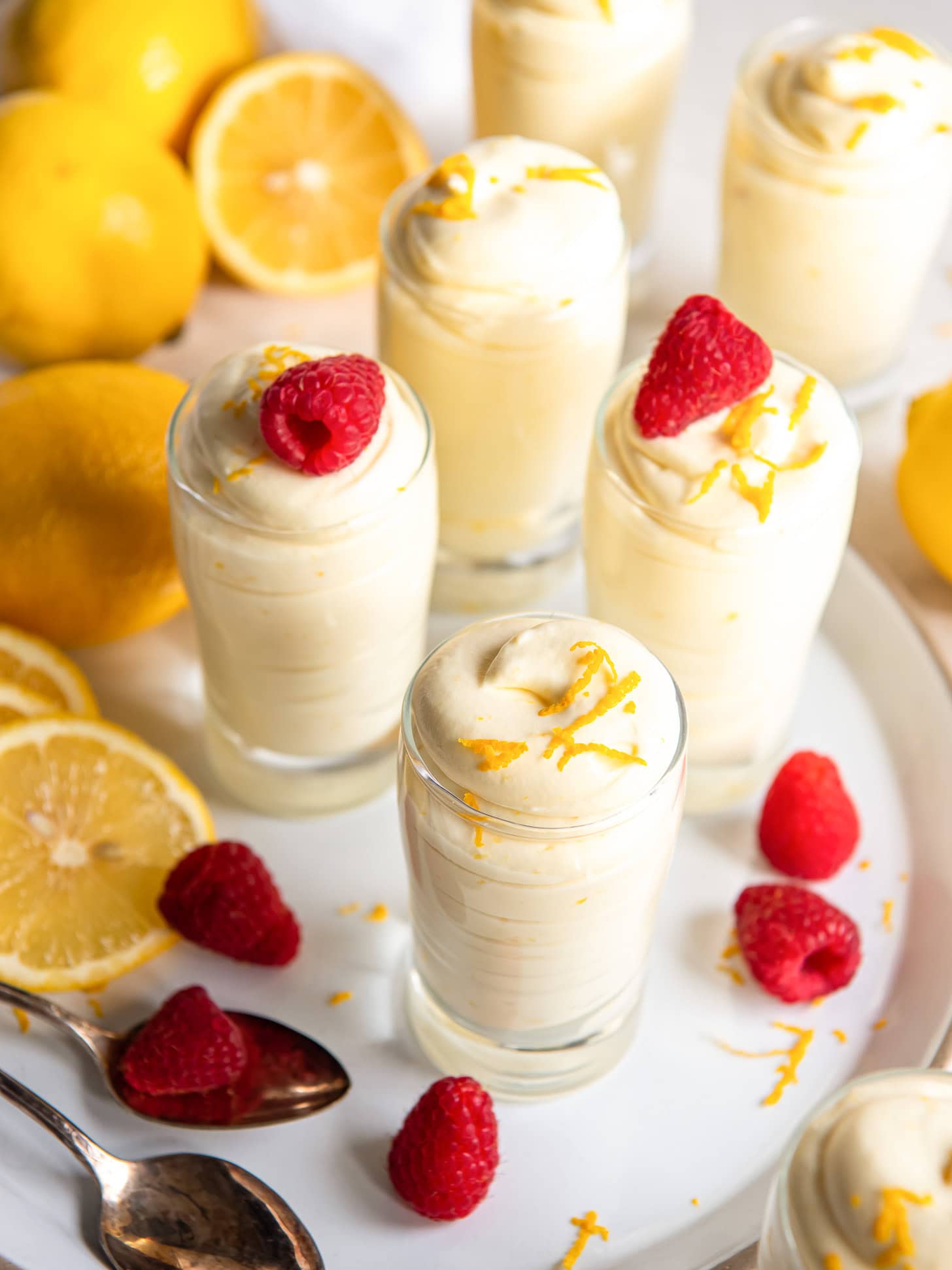 Lemon mousse in small individual glasses served with raspberries.