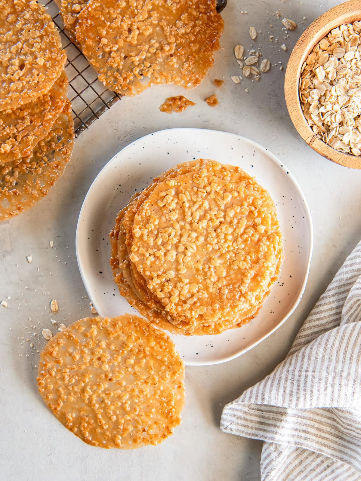 Oatmeal lace cookies stacked on a white plate.