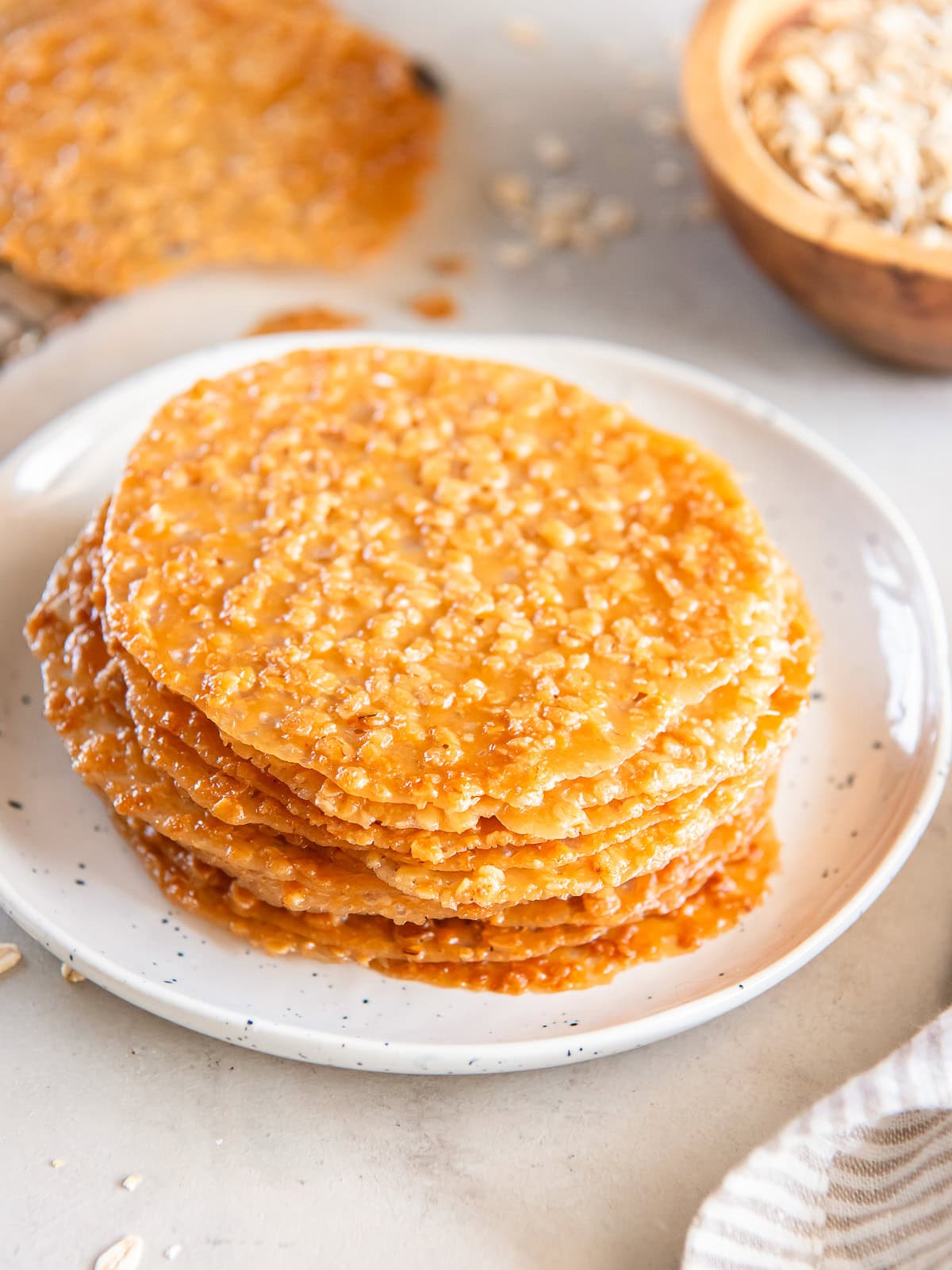 Thin cookies stacked on a white plate.
