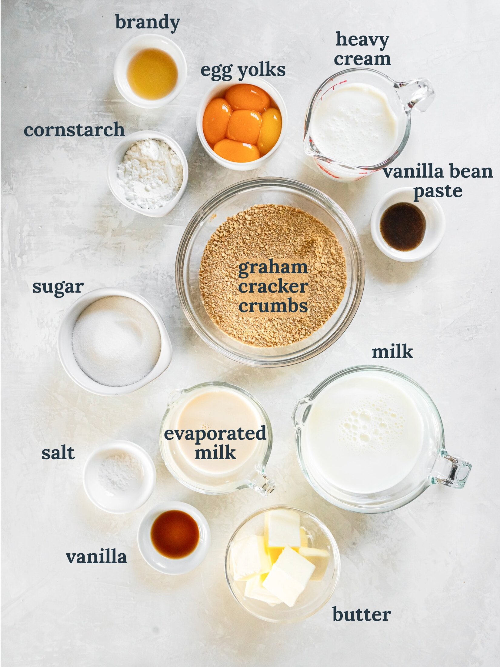 Small bowls with egg yolks, graham cracker crumbs, milk, sugar, vanilla and cornstarch.