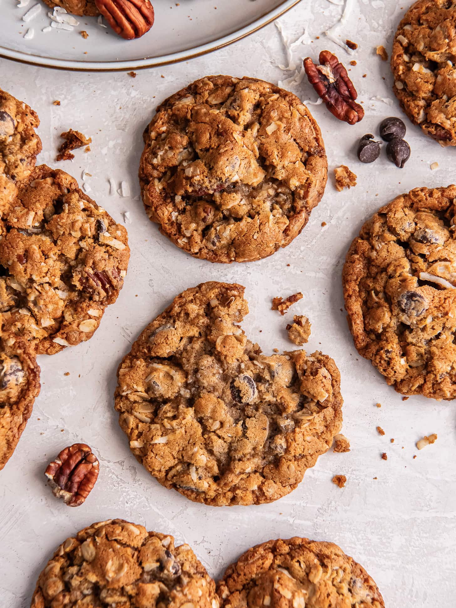 Cowboy cookies on parchment with a bite taken out of one.
