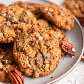 Cowboy cookies on a plate near pecans.