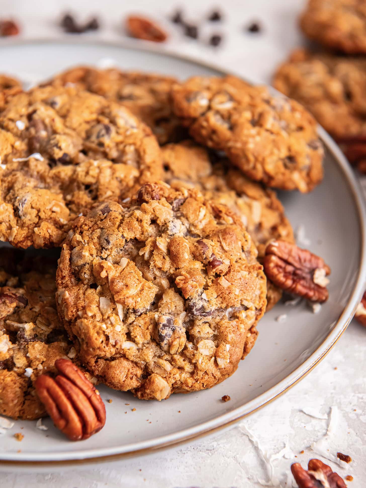 Cowboy cookies on a plate near pecans.