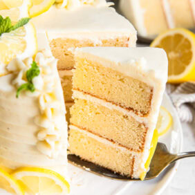 Serving a slice of lemon layer cake off a plate.