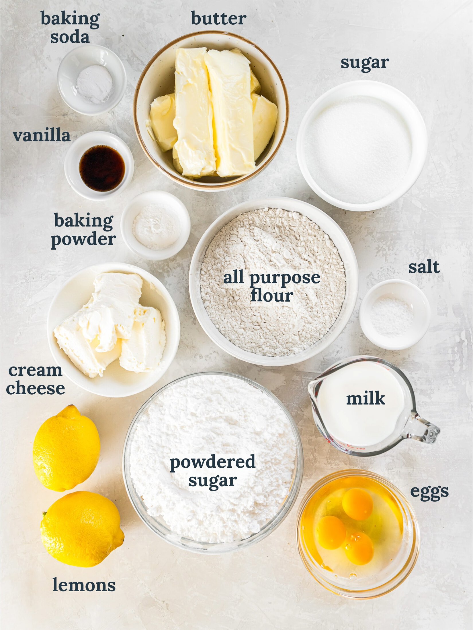 Small bowls with butter, flour, cream cheese powdered sugar, milk and eggs.