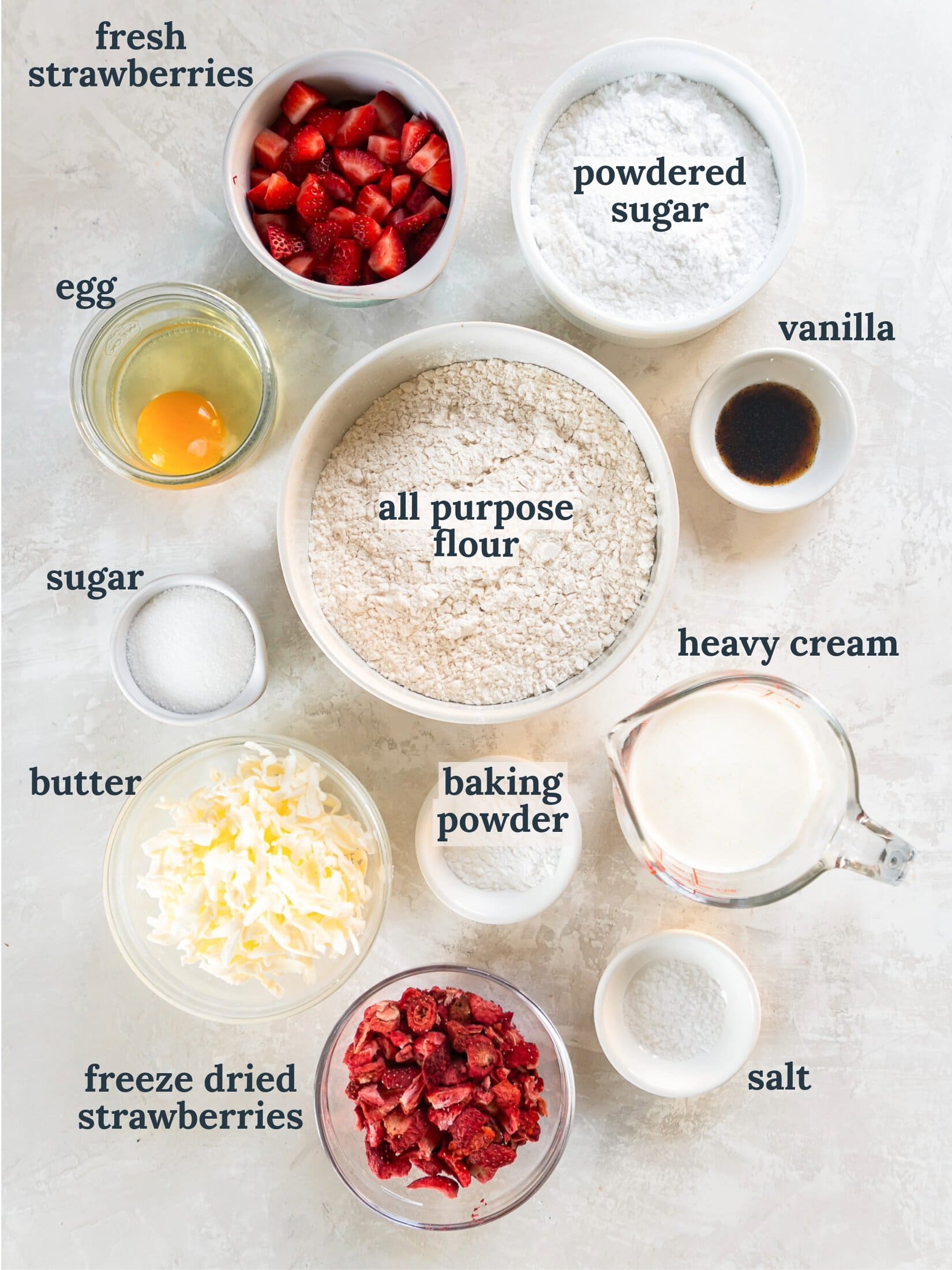 Small bowls with strawberries, flour, egg, butter, cream and vanilla.