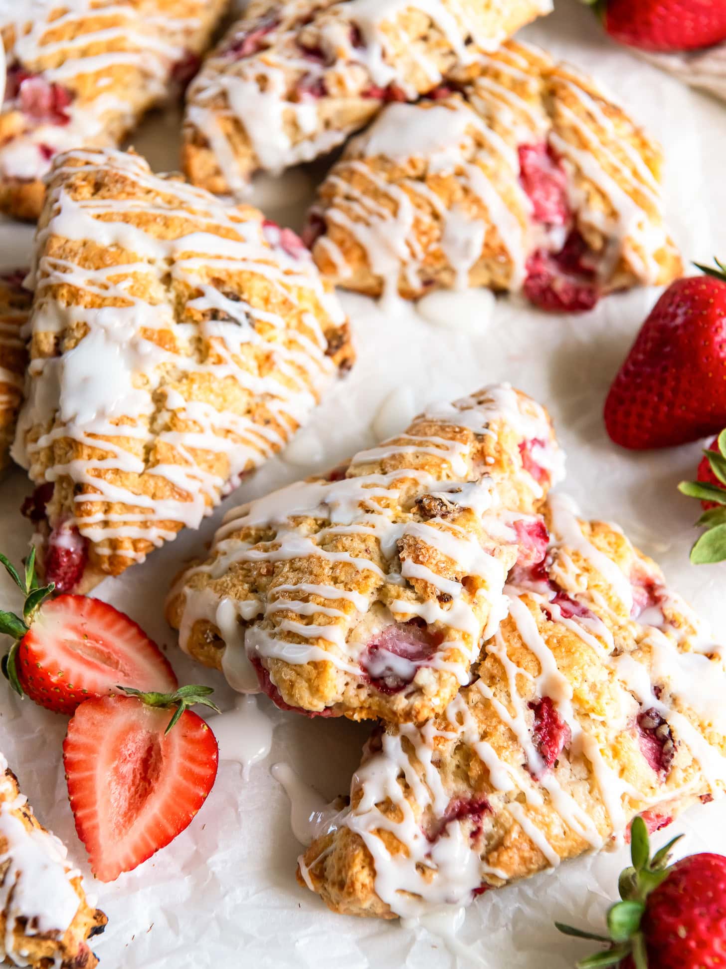 Glazed strawberry scones near halved fresh strawberries.