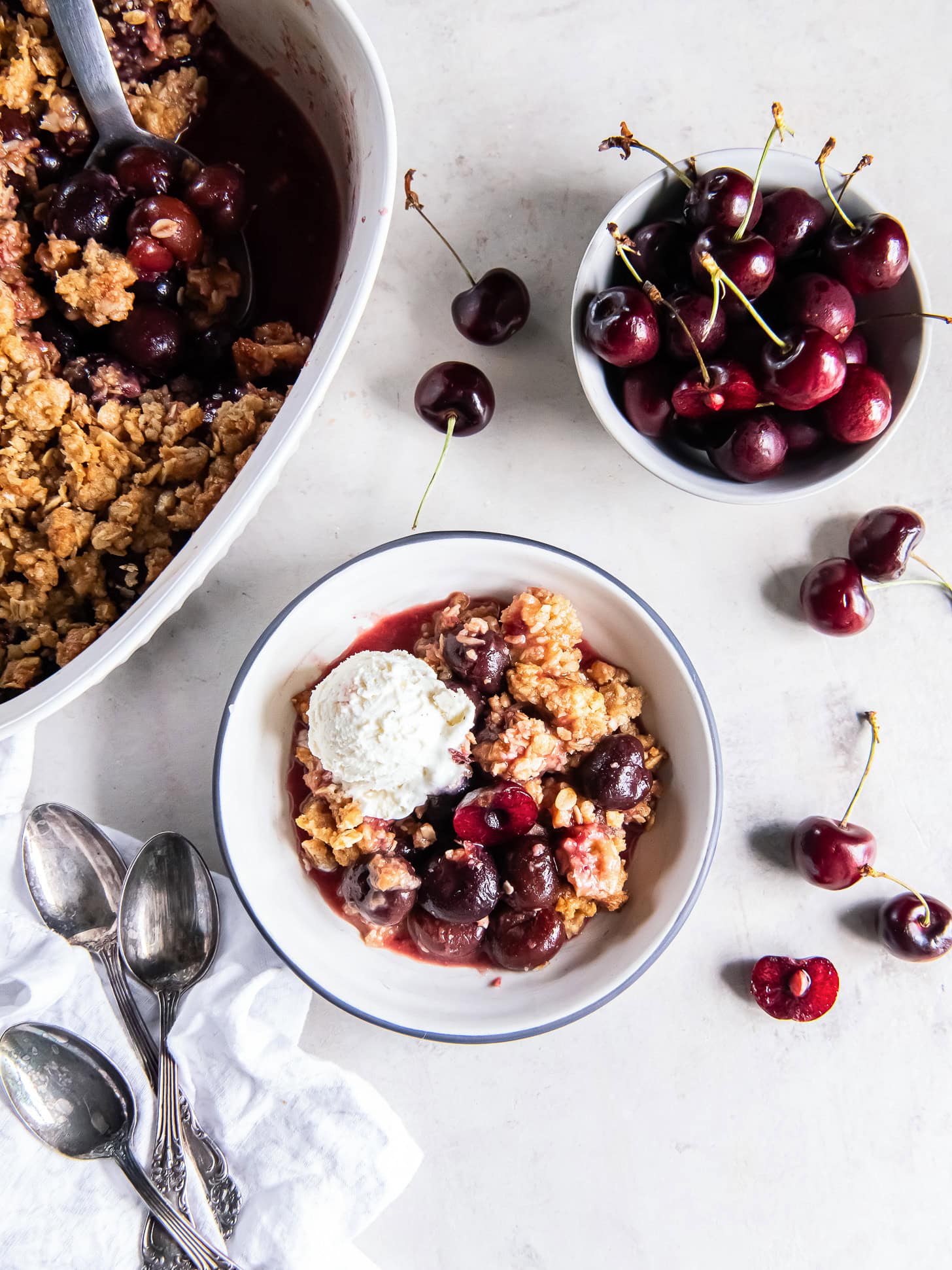Cherry crisp in a bowl with a scoop of vanilla ice cream.