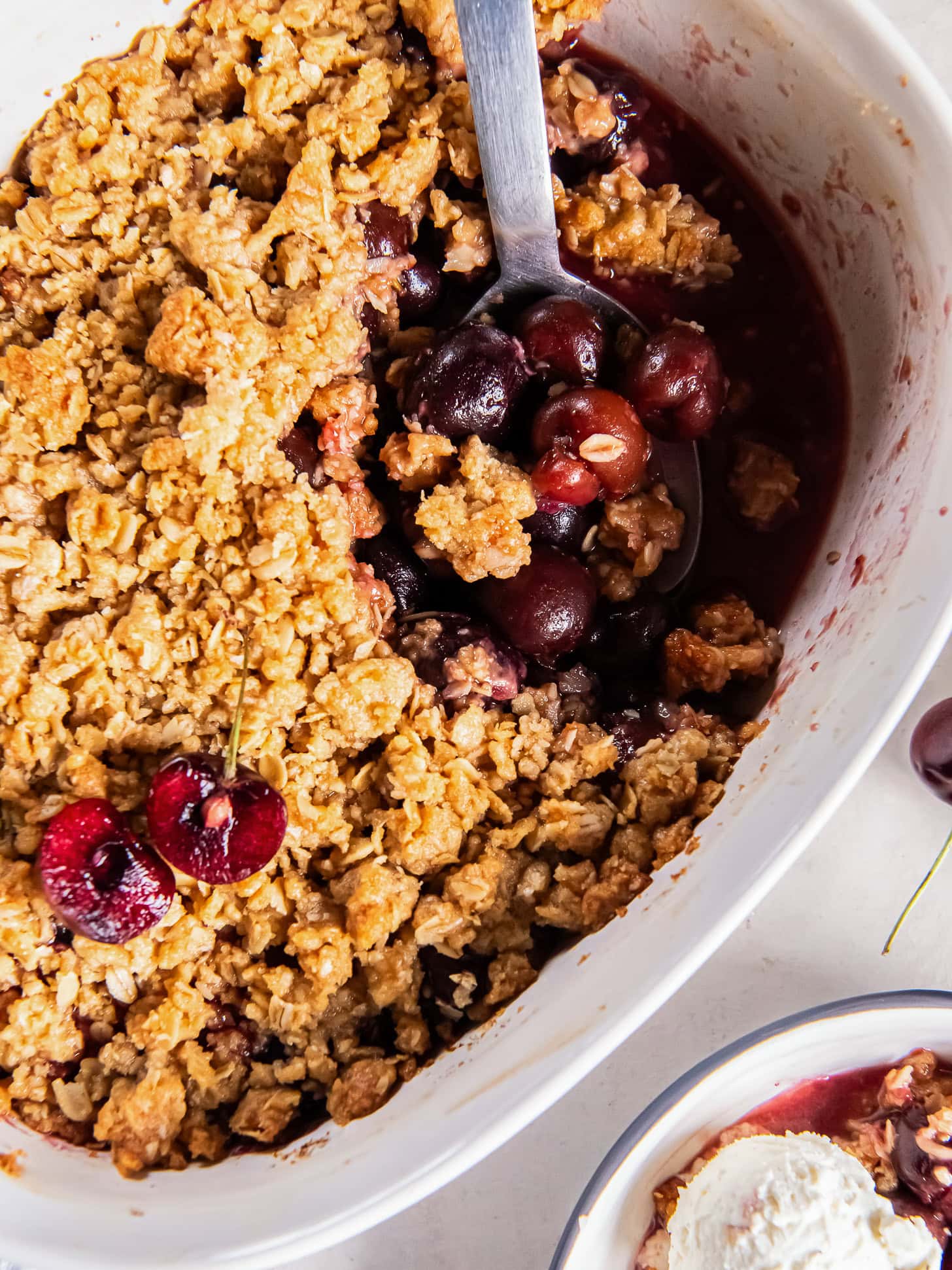 Scooping into a cherry crisp with a large serving spoon.