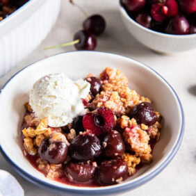 Cherry crisp served with a scoop of vanilla ice cream.