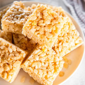 Homemade Rice Krispie treats stacked on a white plate.