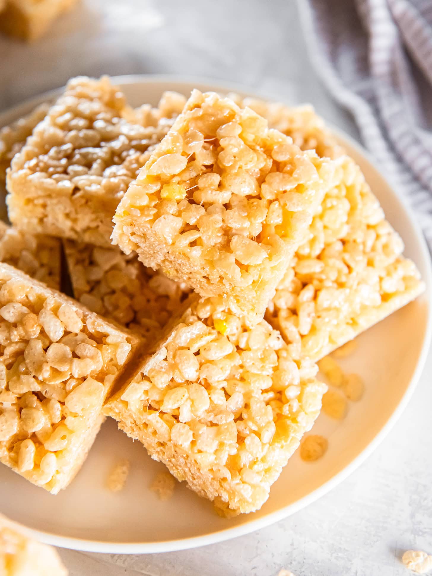 Homemade Rice Krispie treats stacked on a white plate.