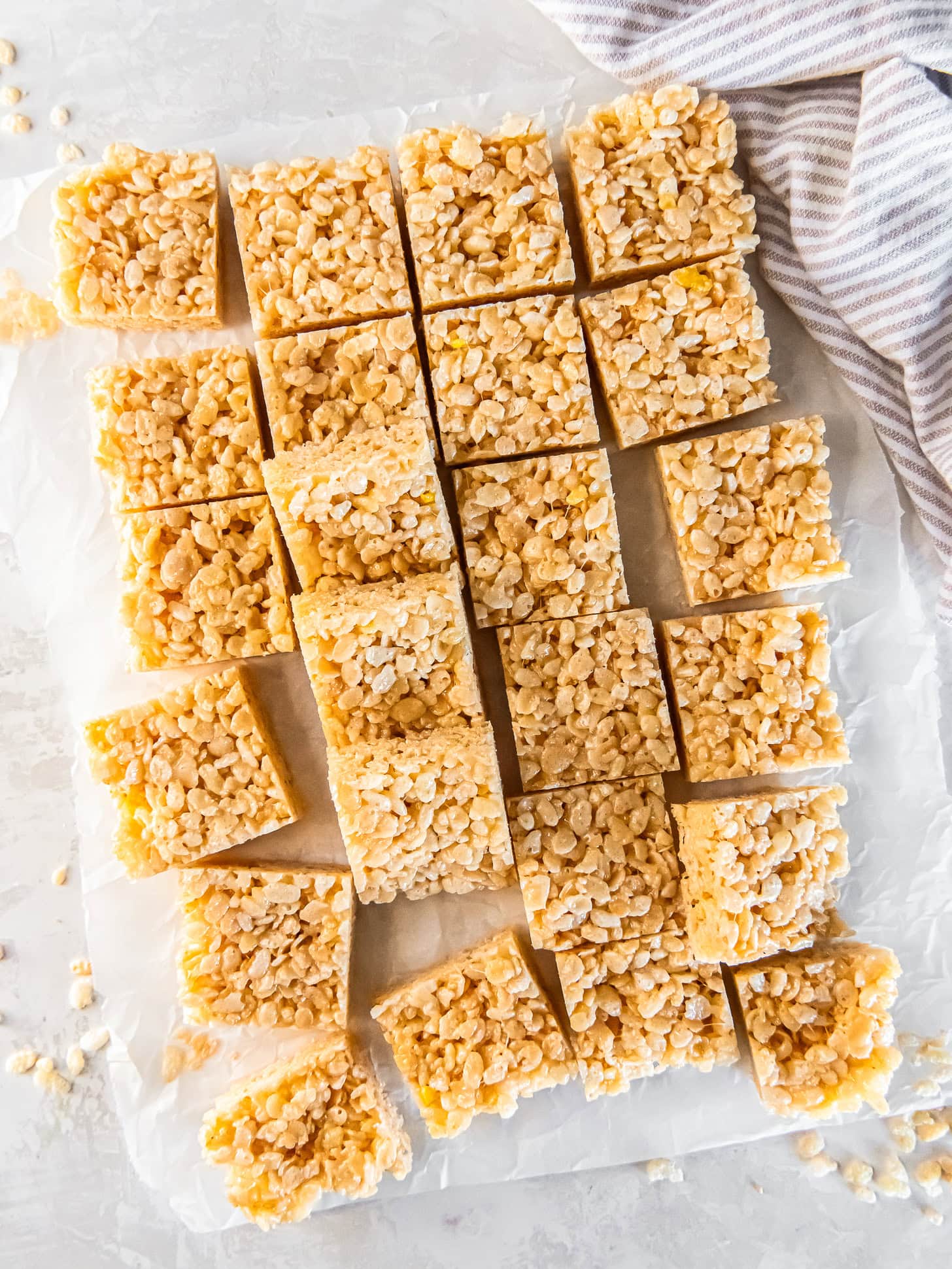 Homemade Rice Krispie Treats cut into squares on parchment.