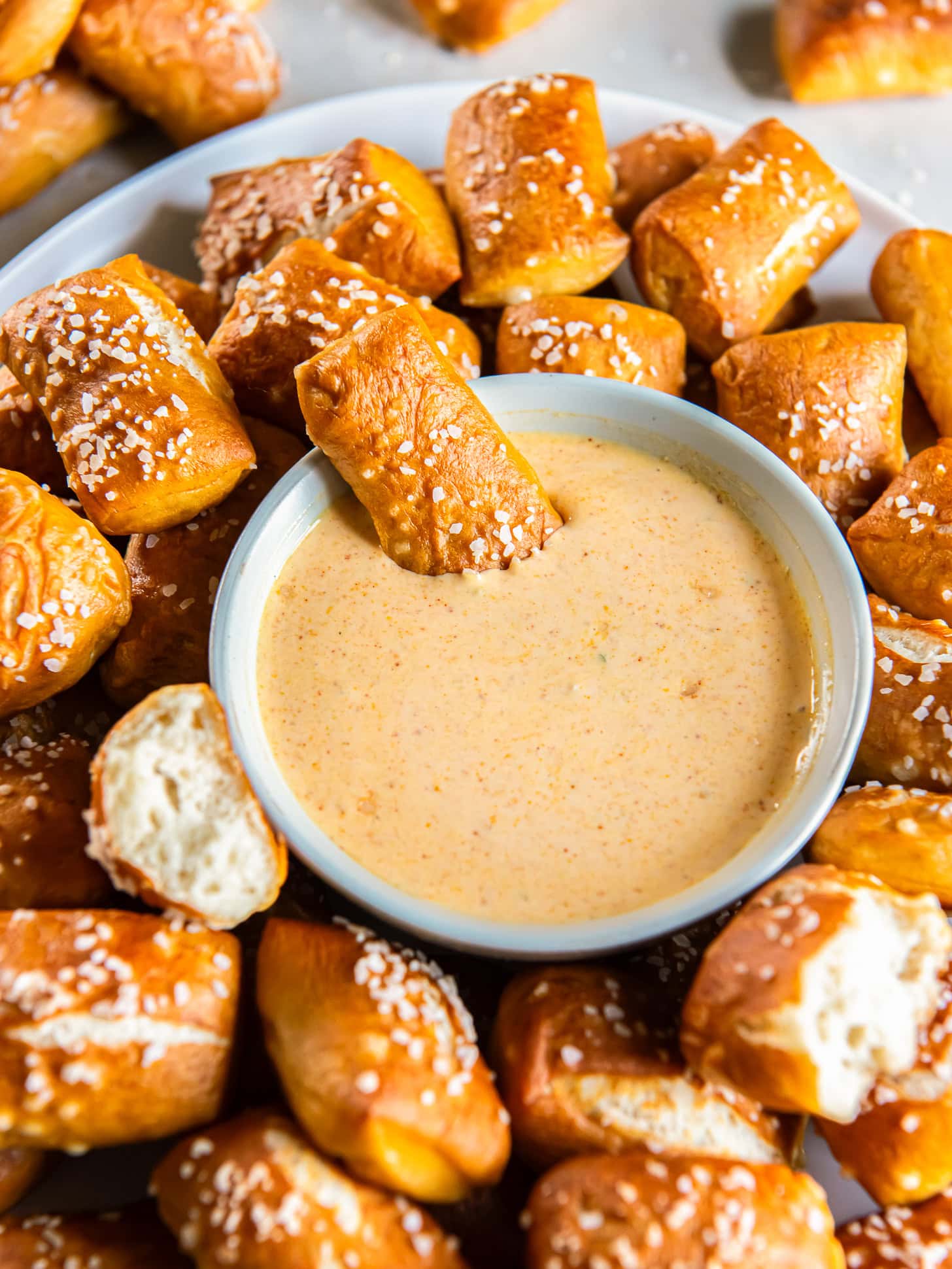 Pretzel bite dipped into a small bowl of cheese sauce.