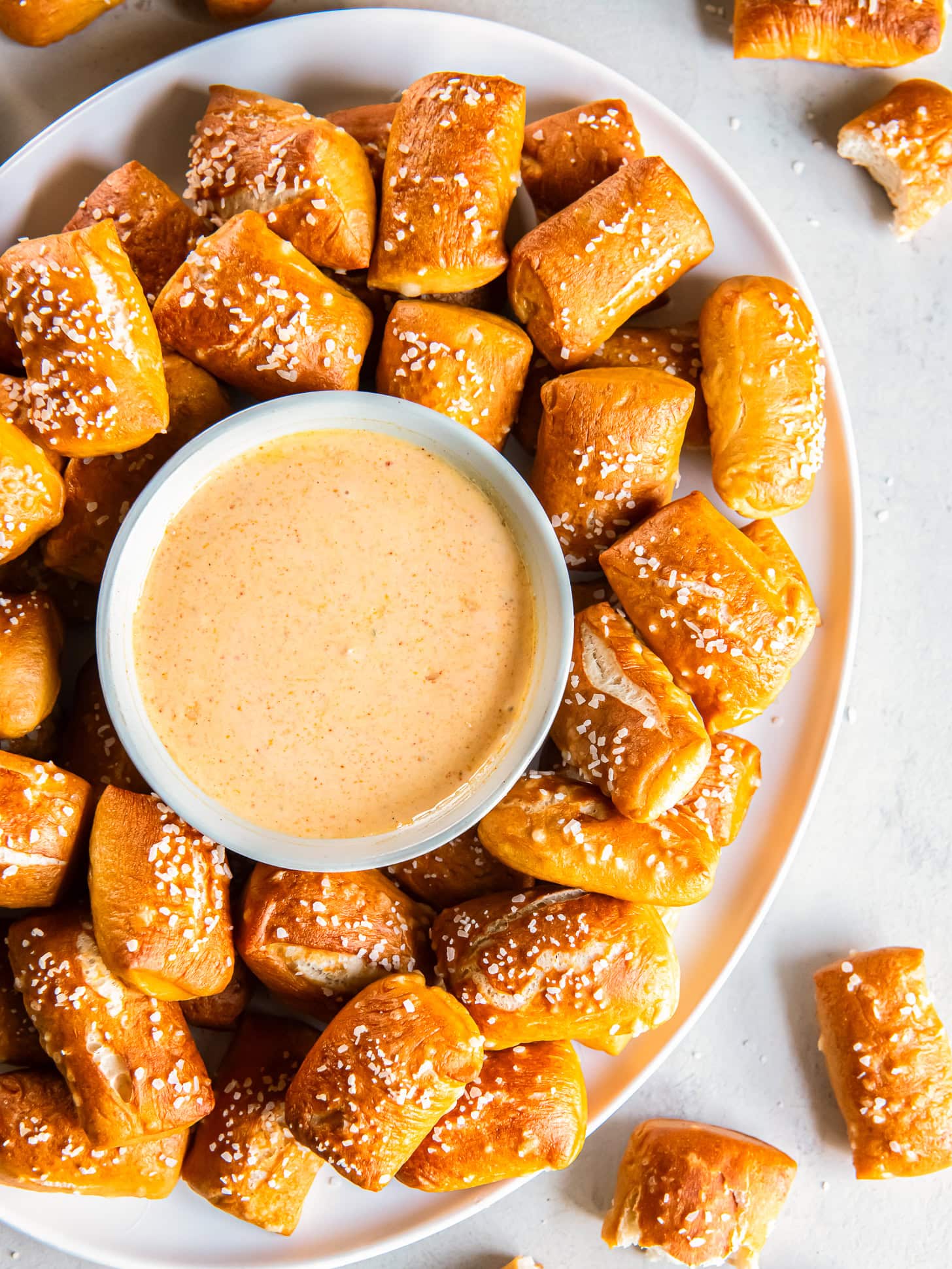 Serving plate with pretzel bites and a small bowl of cheese sauce.
