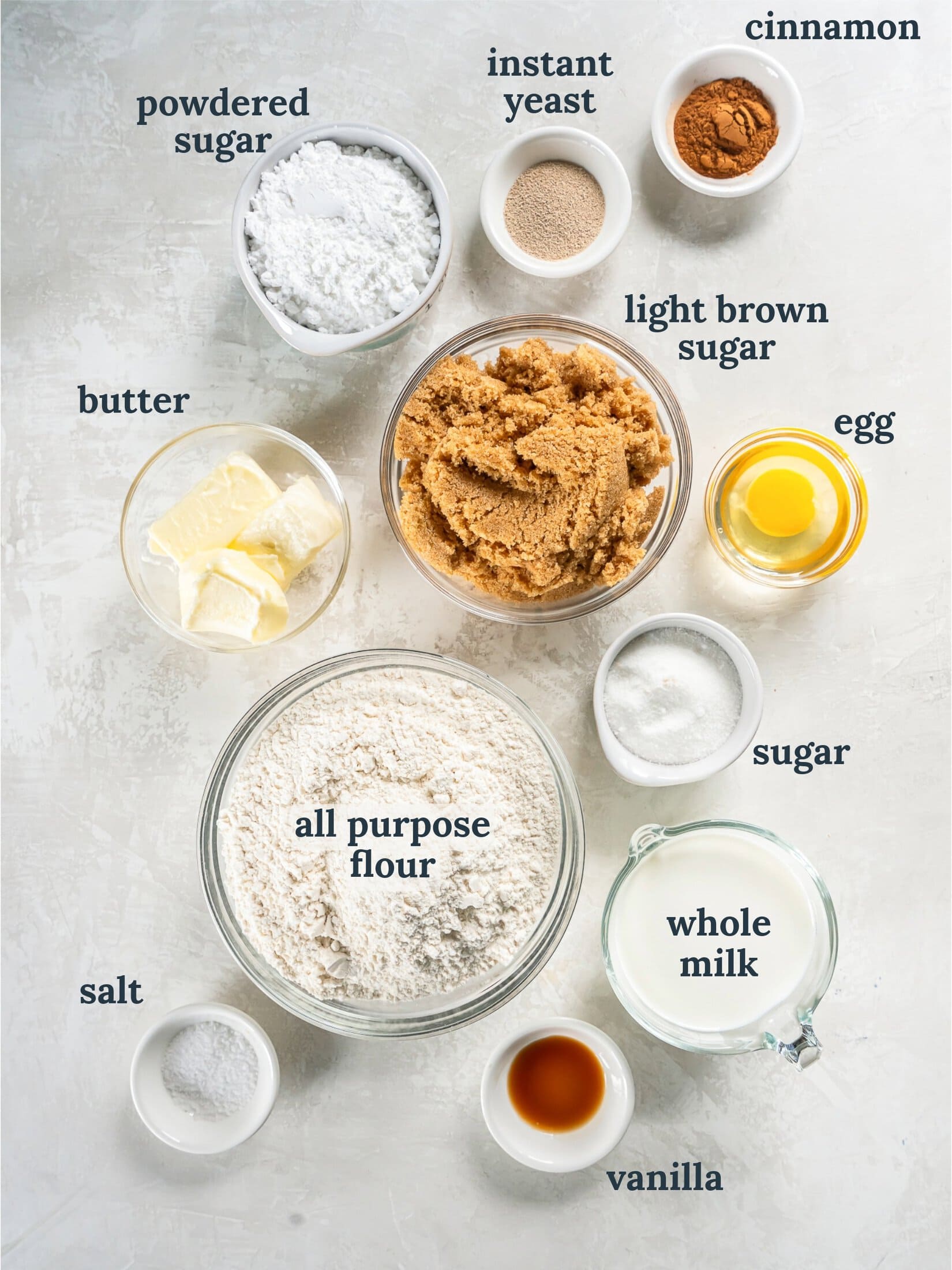 Small bowls with flour, sugar, milk, egg, yeast and butter.